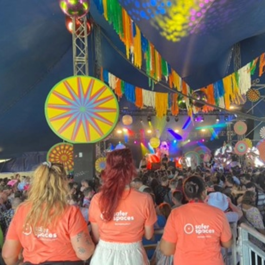 Staff members of safer spaces in orange t-shirt uniforms looking over a crowd at a festival