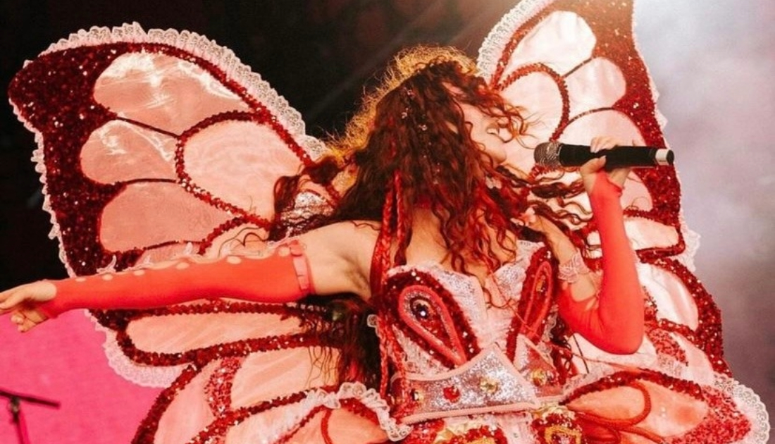Chappell Roan wears a baby pink bodysuit lined with hot pink sequins with large detachable butterfly wings on stage at Coachella 2024 