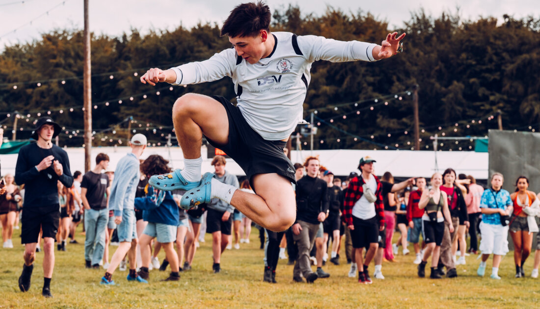 fan doing a high kick in middle of campsite at Reading festival 