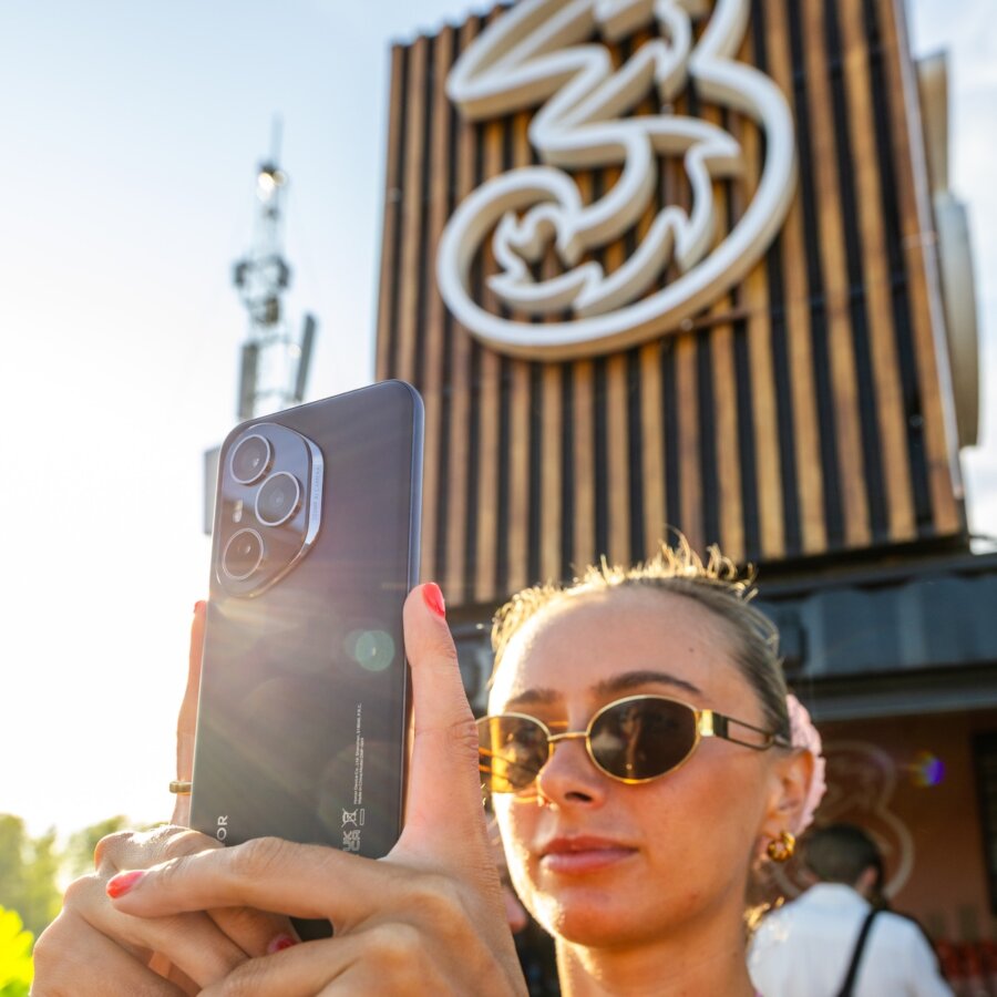 young blonde girl wearing black sun shades holding an iphone 