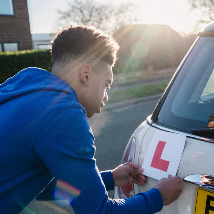 Young Driver attaching learner sign to their car 